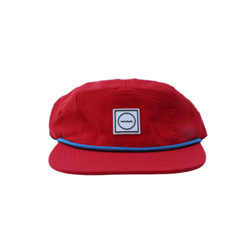 A red five-panel nylon hat with a blue rope detail and a white patch on the front.
