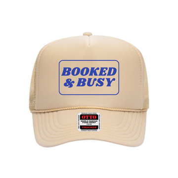 Beige trucker hat with 'Booked & Busy' text on a white background