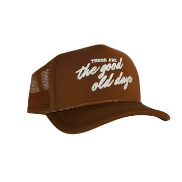 A brown trucker hat with mesh trim and a front panel featuring the text 'These are the good old days' in white.