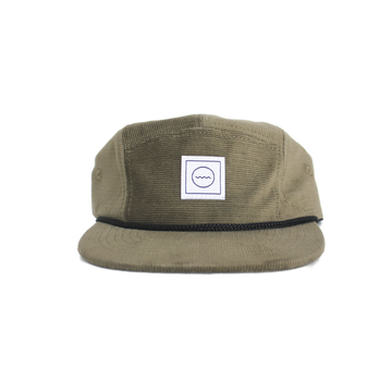 A green corduroy five-panel hat with a black rope detail around the crown, an adjustable velcro back, and fabric eyelets on the side panels. A white square logo with a symbol is visible on the front.