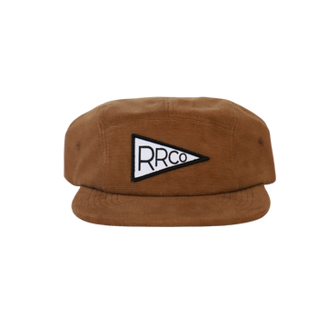 A brown five-panel corduroy hat with a black and white embroidered pennant logo on the front, featuring an adjustable velcro back and fabric eyelets on the side.