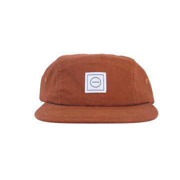 A brown cotton five-panel hat with an adjustable velcro back and fabric eyelets, featuring a white square logo on the front.