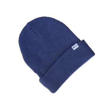 A blue waffle knit beanie with a fold-over cuff, displayed on a neutral background.