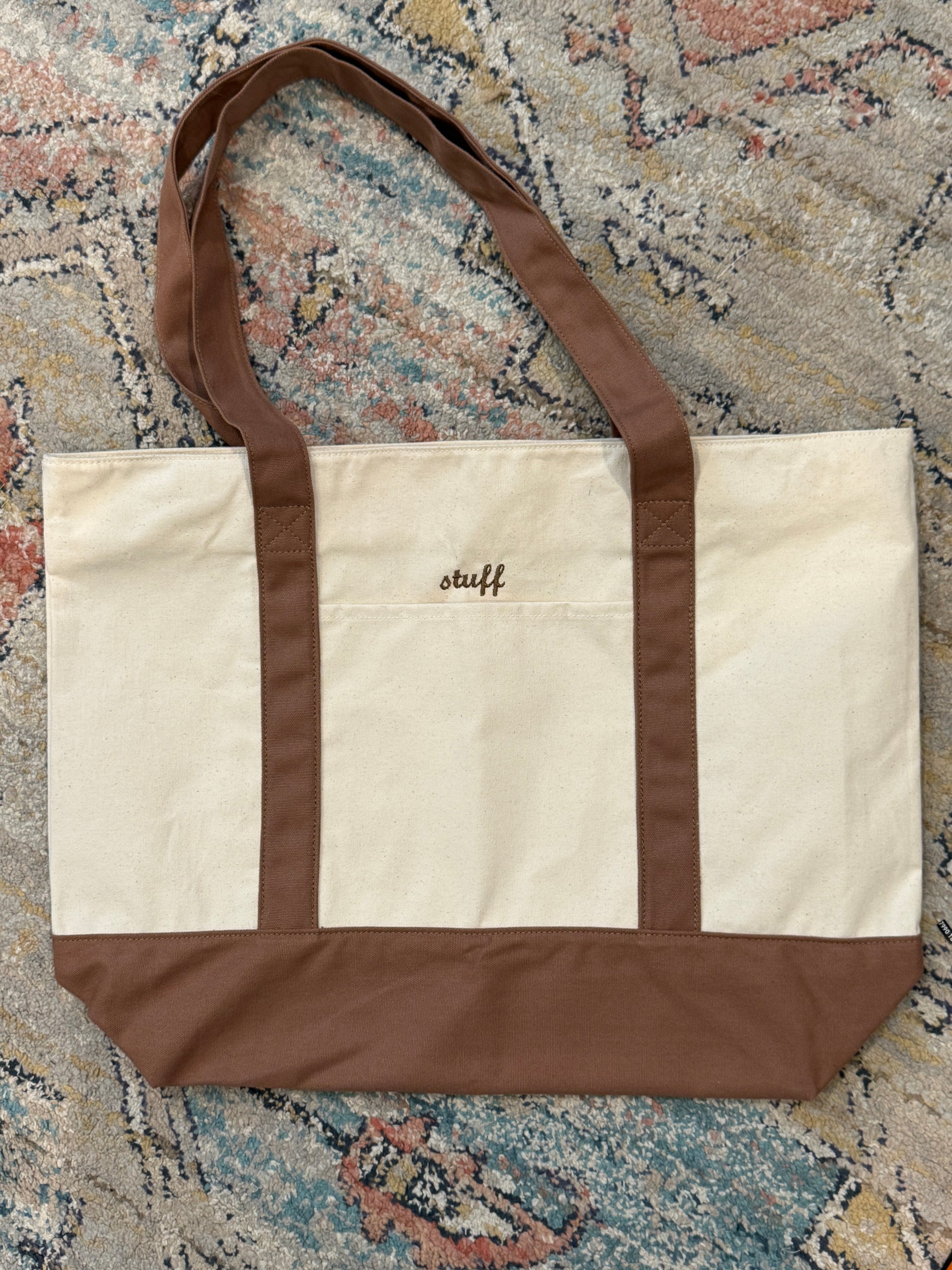 Beige and brown bag with 'Wu' logo on a patterned rug