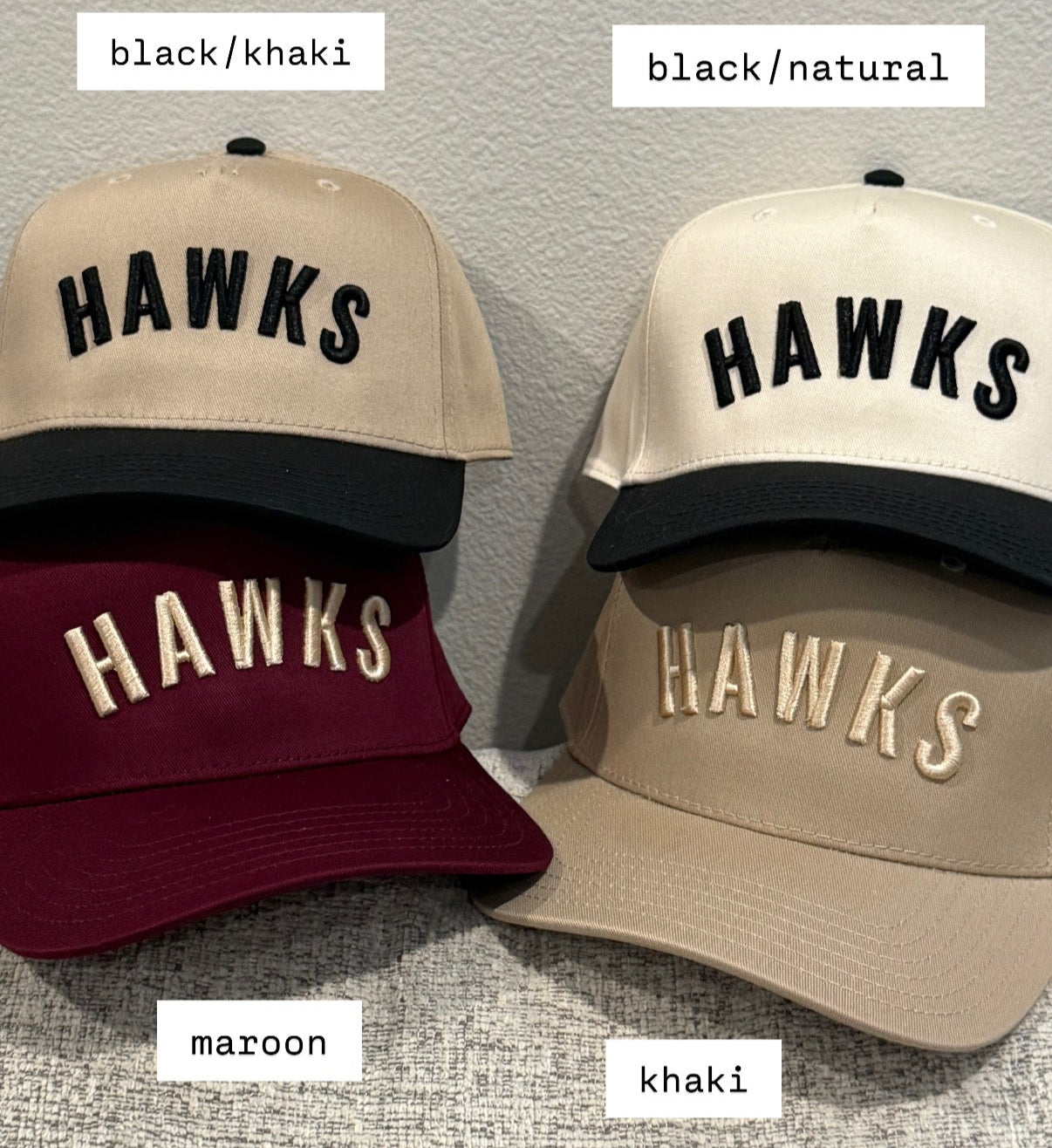 Four 'HAWKS' caps in different colors on a gray background